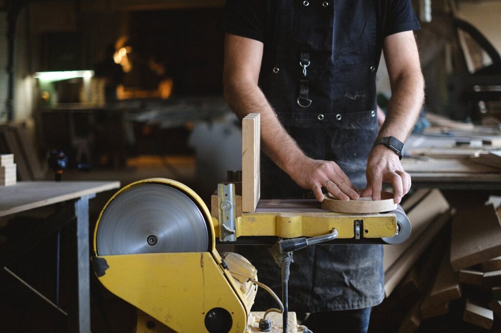 Crop carpenter shaping wooden detail with grinding machine